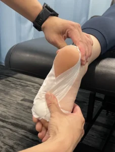 Physiotherapist in Burlington taping young athlete’s foot for sports injury prevention and recovery