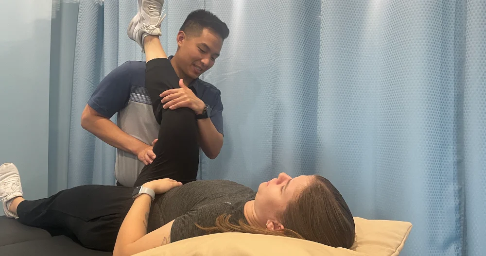 Physiotherapist in Burlington treating patient with leg stretch for summer sports injury recovery